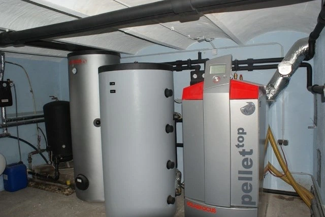 Pelletheizung mit Pufferspeicher und Verrohrung in einem Technikraum.